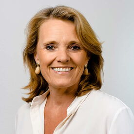 Lächelnde Frau mit kurzen blonden Haaren und weißer Bluse